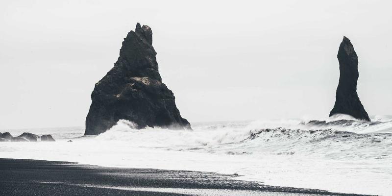 A large, modern extendable dining table made of dark wood with a butterfly leaf mechanism partially extended, showcasing its versatility for entertaining. It is surrounded by stylish, upholstered dining chairs.