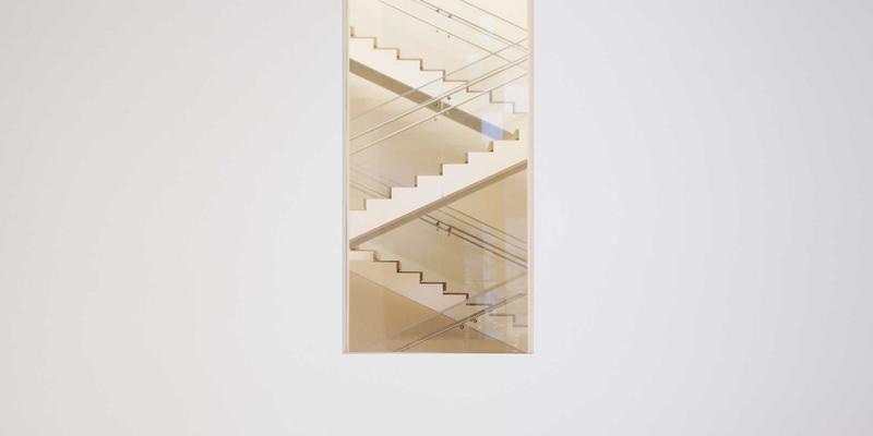 A stylish daybed with plush cushions and throw pillows, positioned against a light grey wall with modern abstract art, serving as both a comfortable bed and an inviting seating area.